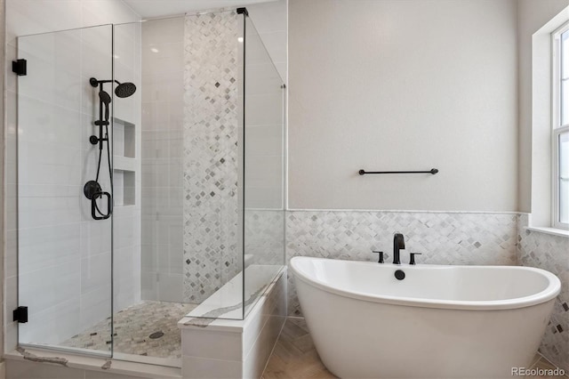 full bath featuring a wainscoted wall, a soaking tub, and tile walls