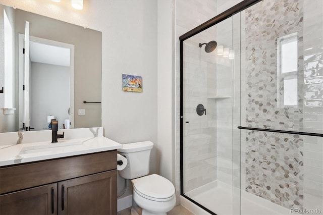 full bathroom featuring vanity, a shower stall, and toilet