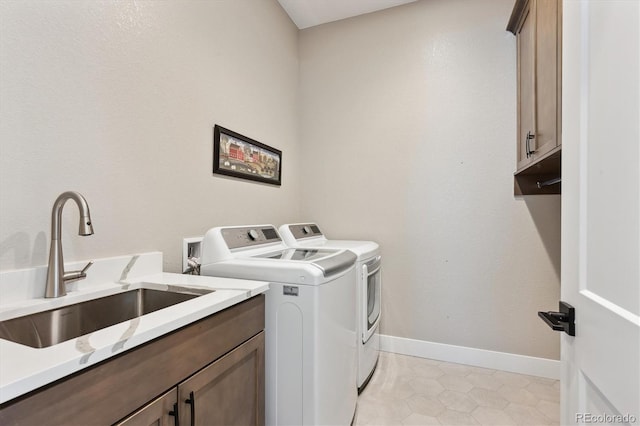 laundry room featuring a sink, washing machine and clothes dryer, cabinet space, and baseboards