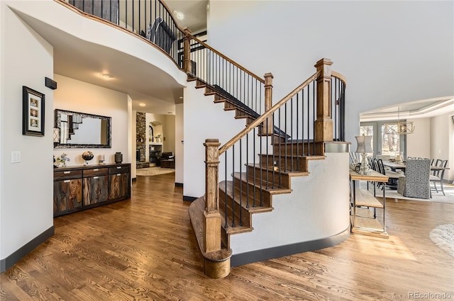 staircase featuring a high ceiling, wood finished floors, and baseboards