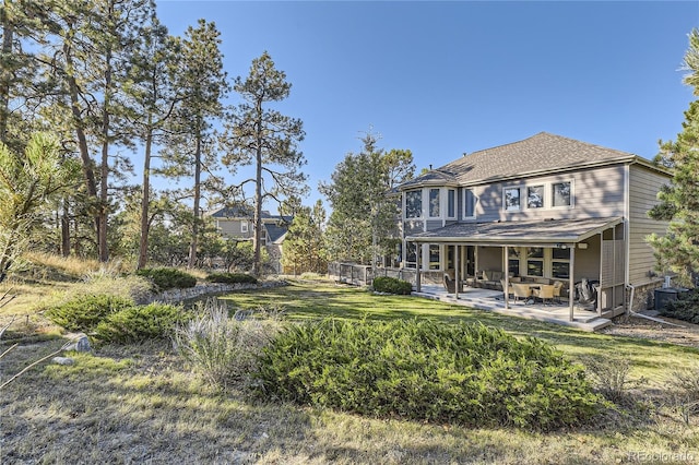 rear view of house with a yard and roof with shingles