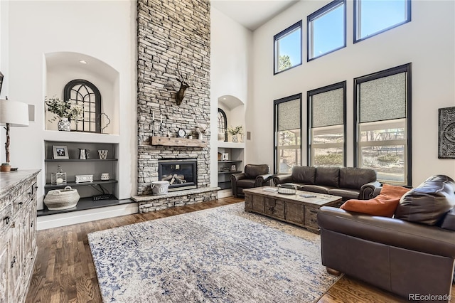 living room featuring a fireplace, a towering ceiling, and wood finished floors