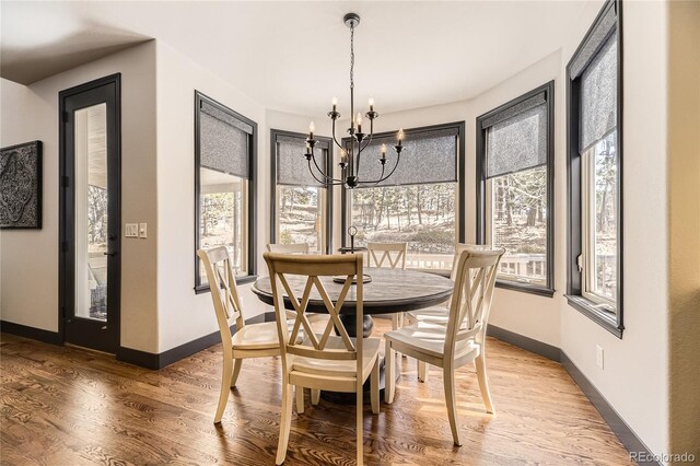 dining area featuring baseboards, an inviting chandelier, and light wood-style flooring