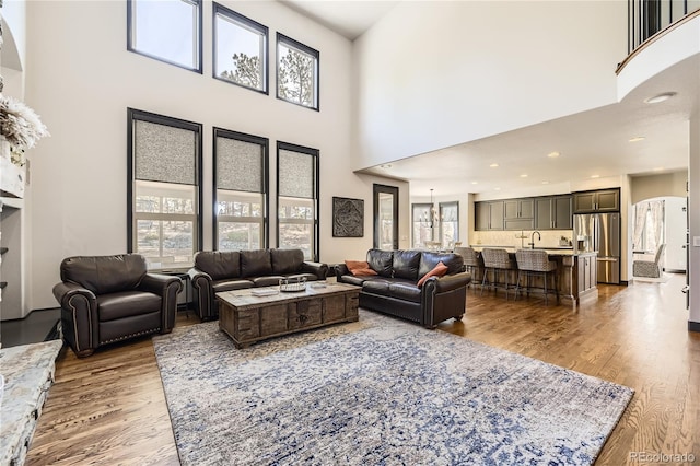 living room with arched walkways, recessed lighting, a high ceiling, and wood finished floors