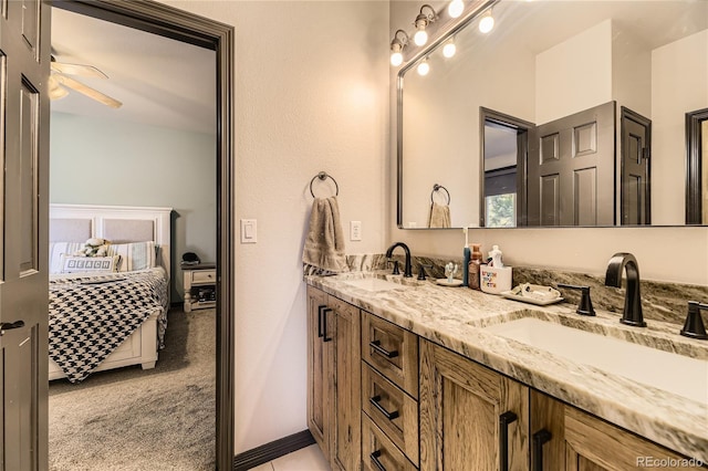 full bath featuring double vanity, connected bathroom, baseboards, and a sink