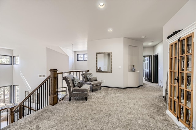 living area with recessed lighting, visible vents, an upstairs landing, and carpet