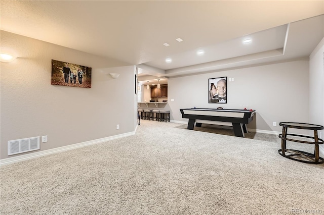 recreation room featuring visible vents, baseboards, a raised ceiling, and carpet flooring