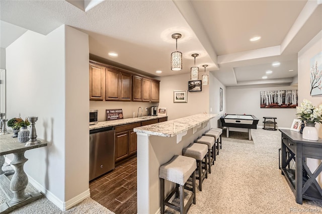 kitchen with wood tiled floor, a breakfast bar, light stone counters, recessed lighting, and appliances with stainless steel finishes