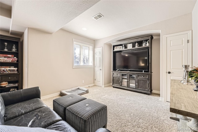 living room with a textured ceiling, baseboards, visible vents, and light carpet