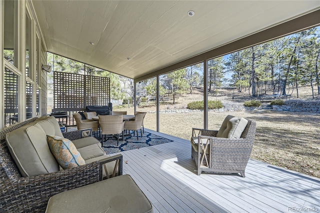 wooden terrace with outdoor dining space, a trampoline, and an outdoor hangout area