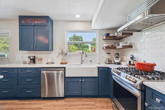 8445 Lamar Dr, Arvada, CO 80003 - kitchen with appliances with stainless steel finishes, decorative backsplash, blue cabinetry, light countertops, and light wood finished floors