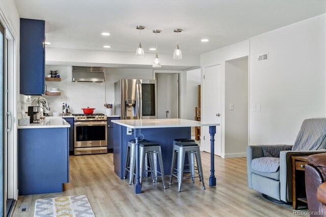 8445 Lamar Dr, Arvada, CO 80003 - kitchen with appliances with stainless steel finishes, blue cabinets, ventilation hood, a kitchen bar, and light countertops