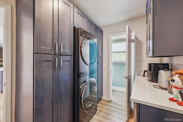 8445 Lamar Dr, Arvada, CO 80003 - laundry room featuring stacked washer / drying machine, light wood-style floors, and cabinet space