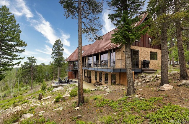 116 Ramona Rd, Golden, CO 80403 - back of property featuring stone siding, a patio area, a standing seam roof, and metal roof