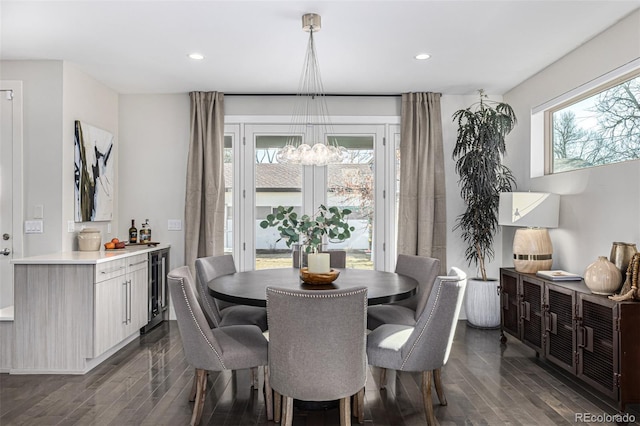 dining space with dark wood-type flooring, beverage cooler, a notable chandelier, and recessed lighting