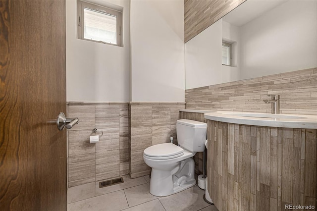 half bathroom featuring visible vents, toilet, wainscoting, tile patterned floors, and vanity