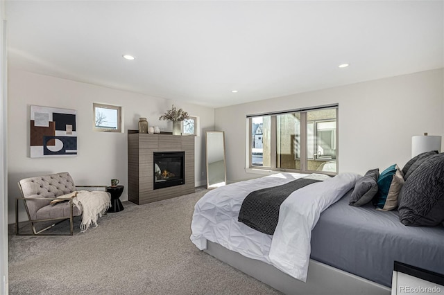 bedroom with recessed lighting, multiple windows, carpet, and a glass covered fireplace