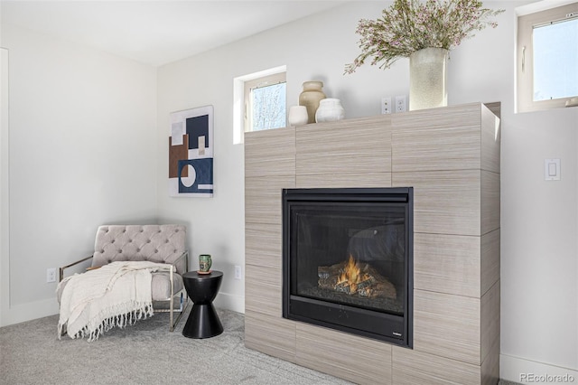 interior space with baseboards, a glass covered fireplace, and carpet flooring