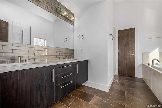 full bath featuring double vanity, tiled tub, tasteful backsplash, and a sink