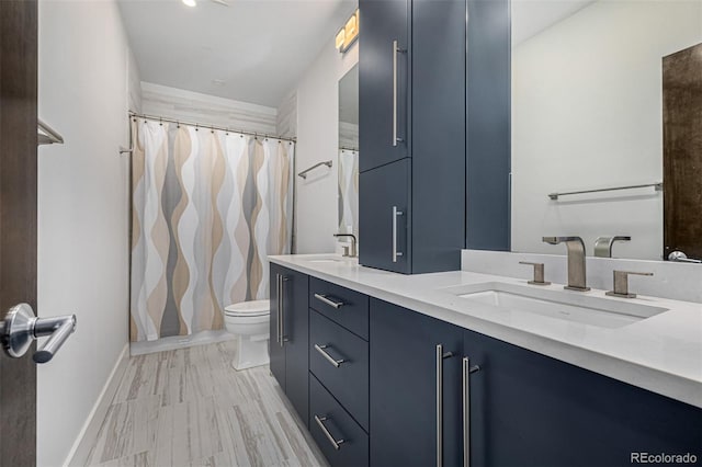 bathroom with double vanity, toilet, baseboards, and a sink