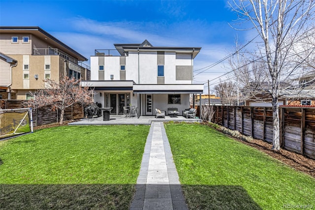 back of property with stucco siding, a lawn, a fenced backyard, and a patio area