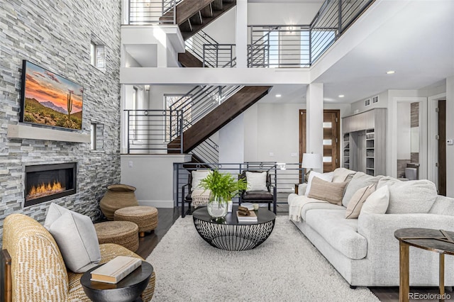 living room with stairs, a towering ceiling, wood finished floors, and a fireplace