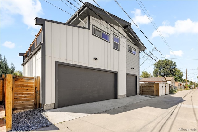 4312 Xavier St, Denver, CO 80212 - view of side of property featuring board and batten siding, an attached garage, fence, and driveway