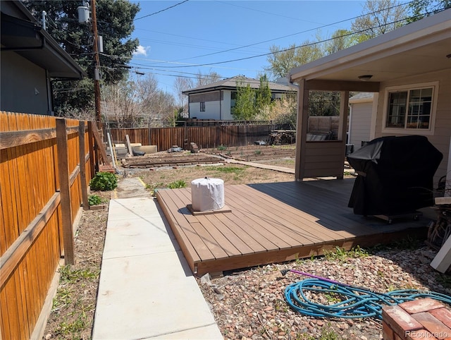 wooden terrace with a fenced backyard and grilling area