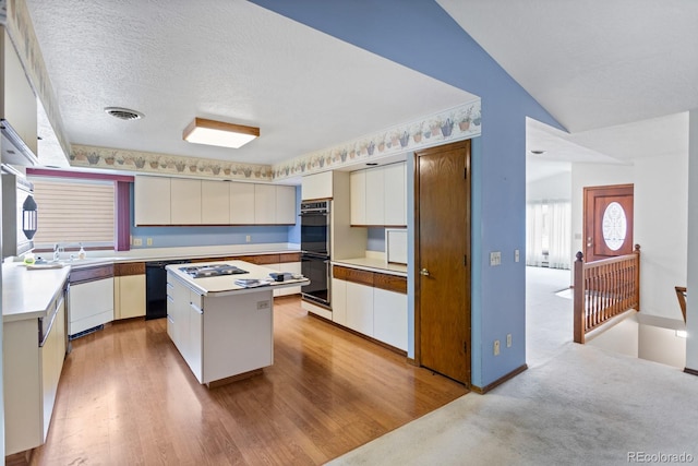 11686 W 74th Way, Arvada, CO 80005 - kitchen with black appliances, a kitchen island, light wood-type flooring, light countertops, and lofted ceiling