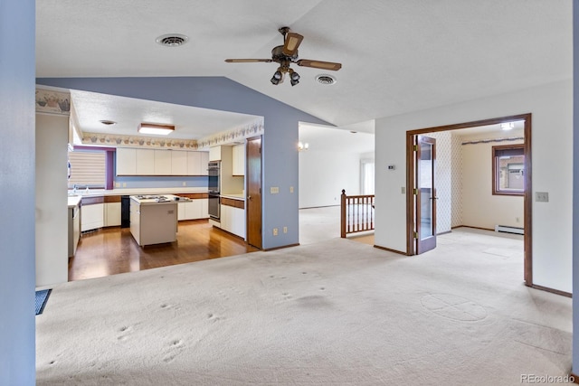 11686 W 74th Way, Arvada, CO 80005 - unfurnished living room featuring light carpet, baseboard heating, lofted ceiling, a ceiling fan, and healthy amount of natural light