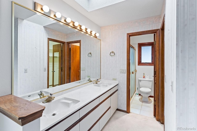 11686 W 74th Way, Arvada, CO 80005 - bathroom featuring a skylight, double vanity, an enclosed shower, and tile patterned flooring