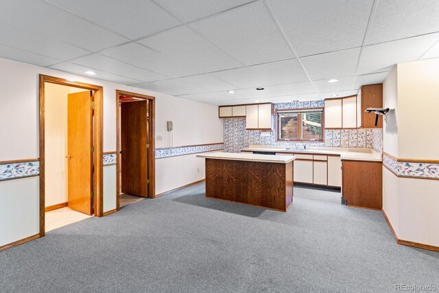 11686 W 74th Way, Arvada, CO 80005 - kitchen with light colored carpet, a center island, a paneled ceiling, light countertops, and white cabinetry