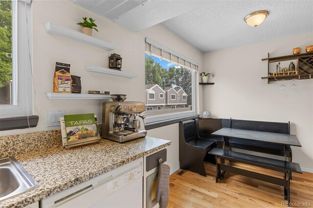 6545 W 84th Way Unit 132, Arvada, CO 80003 - kitchen featuring open shelves, white dishwasher, light wood-style flooring, and a textured ceiling