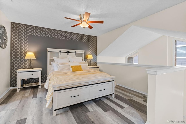 6545 W 84th Way Unit 132, Arvada, CO 80003 - bedroom featuring an accent wall, baseboards, wood finished floors, ceiling fan, and wallpapered walls