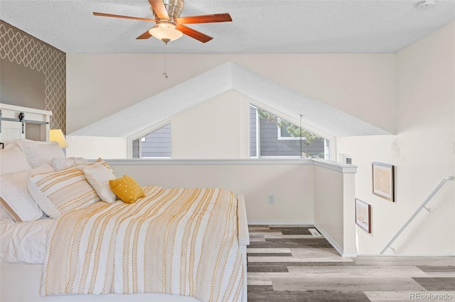 6545 W 84th Way Unit 132, Arvada, CO 80003 - bedroom featuring wood finished floors, a textured ceiling, lofted ceiling, a ceiling fan, and baseboards