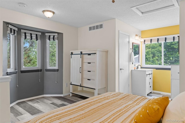 6545 W 84th Way Unit 132, Arvada, CO 80003 - bedroom featuring attic access, light wood-style floors, a textured ceiling, multiple windows, and baseboards