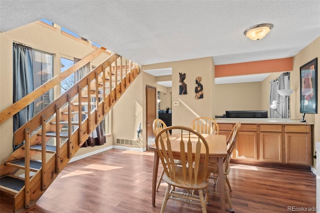 dining area with baseboards, visible vents, stairway, wood finished floors, and a textured ceiling