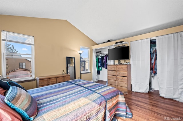 bedroom with lofted ceiling, wood finished floors, and multiple closets