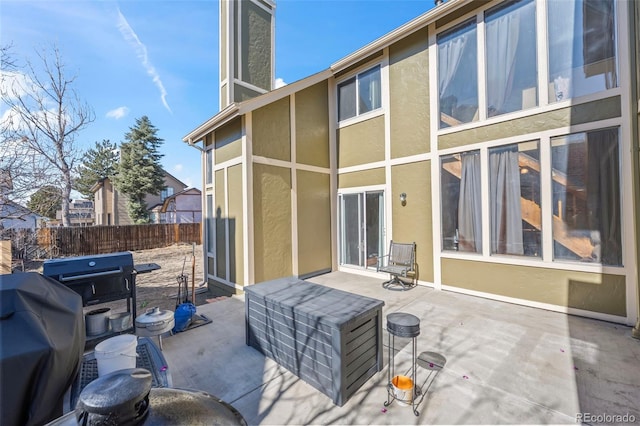 rear view of house featuring a patio area, fence, and stucco siding