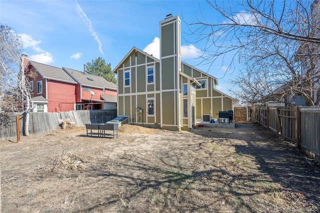 rear view of house featuring a chimney and a fenced backyard