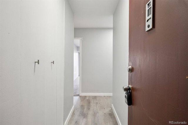 hall featuring light wood-style flooring and baseboards