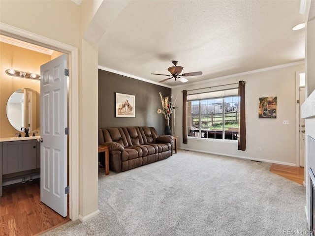 living area with carpet, baseboards, ceiling fan, and ornamental molding