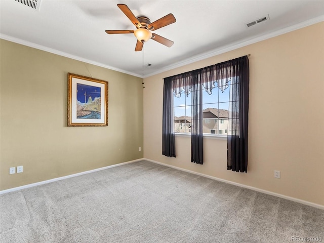 carpeted spare room featuring visible vents, ornamental molding, baseboards, and ceiling fan