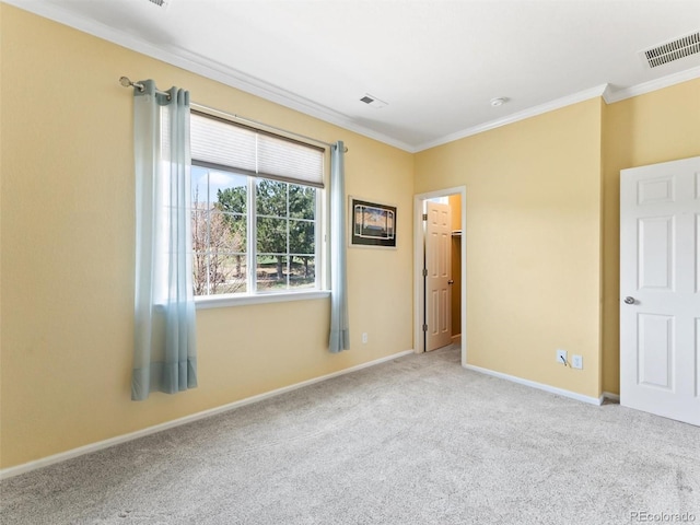 empty room with visible vents, carpet, crown molding, and baseboards