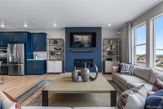 living room featuring a textured ceiling, light hardwood / wood-style floors, and a wealth of natural light