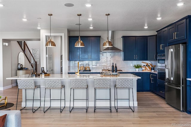 kitchen featuring stainless steel appliances, a center island with sink, blue cabinets, and a breakfast bar