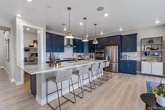 kitchen with wall chimney exhaust hood, light hardwood / wood-style floors, a breakfast bar area, stainless steel appliances, and hanging light fixtures