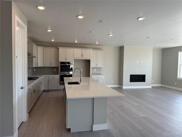 kitchen featuring white cabinetry, sink, a center island with sink, and light hardwood / wood-style flooring