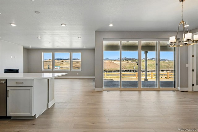 kitchen featuring baseboards, open floor plan, a chandelier, and light countertops