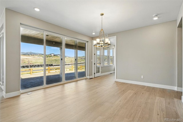 unfurnished dining area featuring baseboards, a chandelier, and light wood-style floors